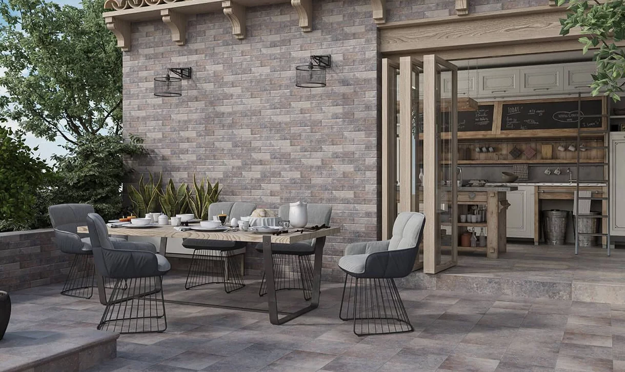 Rustykalny taras jadalny z płytkami kamieniopodobnymi na podłodze i ścianach oraz drewnianymi elementami.