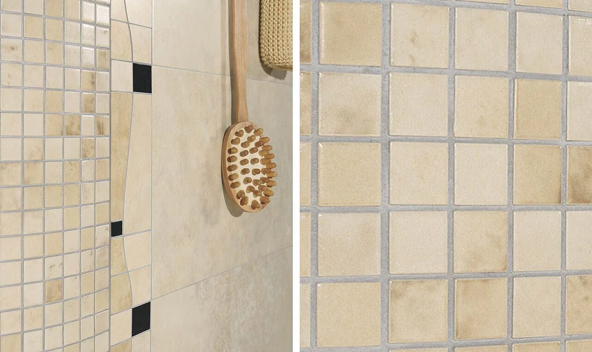 Zbliżenie na ścianę łazienki z beżowymi mozaikowymi i dużymi ceramicznymi płytkami oraz drewnianą szczotką do kąpieli.