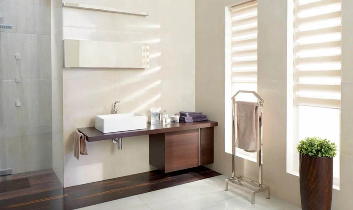 Nowoczesna łazienka z jasnobeżowymi płytkami kamieniopodobnymi na ścianach i ciemnymi płytkami drewnopodobnymi w prysznicu i pod umywalką.