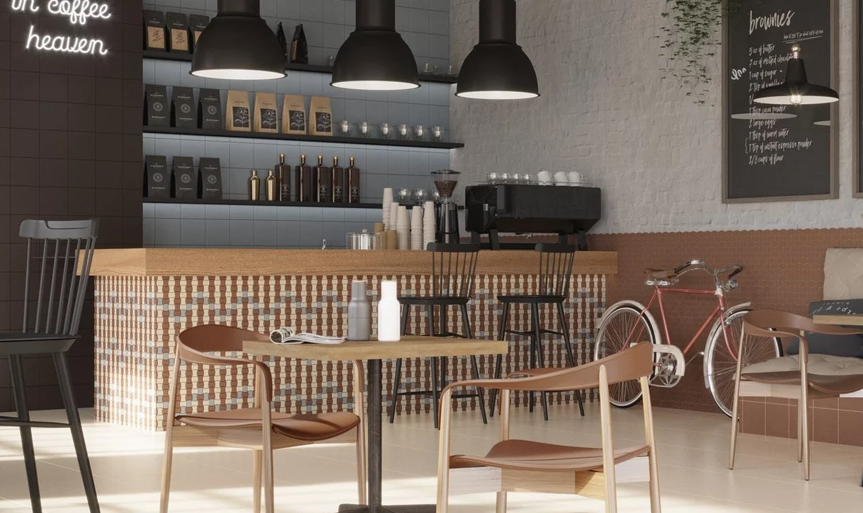 Przytulna kawiarnia z mozaiką płytek kamieniopodobnych na ladzie i jasnobeżowymi płytkami na podłodze.