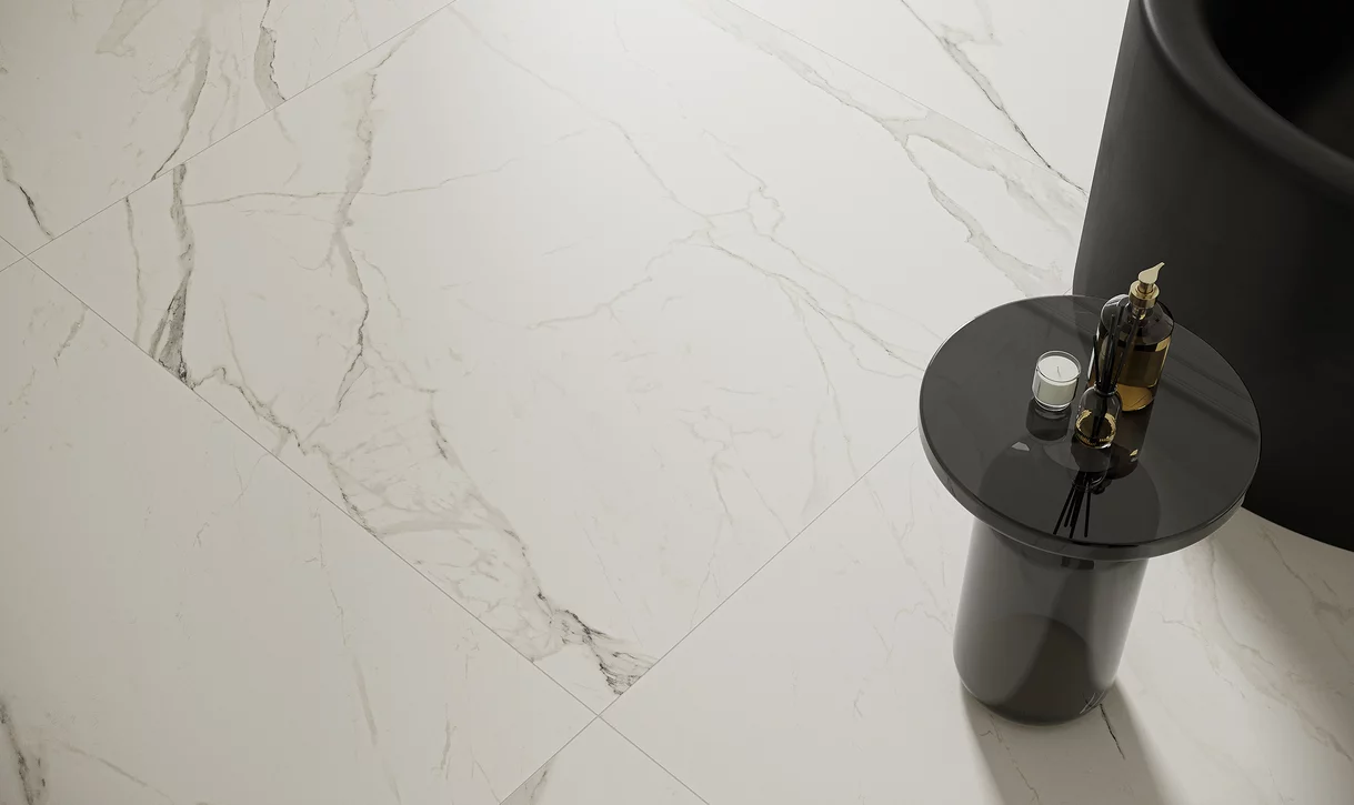 Zbliżenie na błyszczące białe płytki marmurowe z kolekcji Calacatta i nowoczesny czarny stolik.