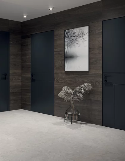 Minimalistyczny przedpokój z jasnoszarymi płytkami inspirowanymi kamieniem z kolekcji Lightstone i ciemnymi płytkami drewnopodobnymi.