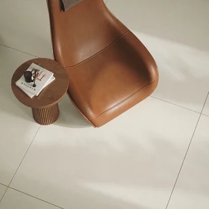 Nowoczesny kącik do czytania z beżowymi płytkami Mild Desert, skórzanym fotelem i okrągłym stolikiem.