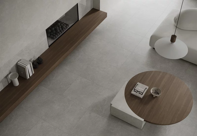 Minimalistyczny salon z dużymi płytkami inspirowanymi kamieniem z kolekcji Minirock i drewnianymi meblami.