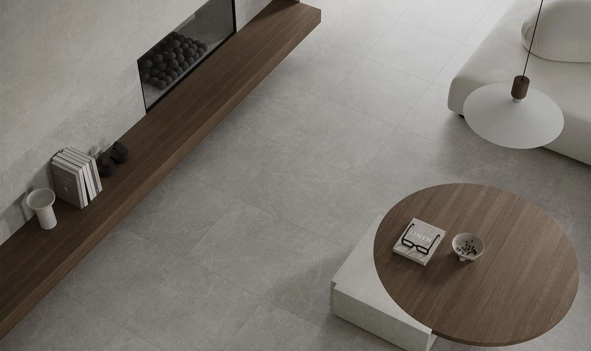 Minimalistyczny salon z dużymi płytkami inspirowanymi kamieniem z kolekcji Minirock i drewnianymi meblami.