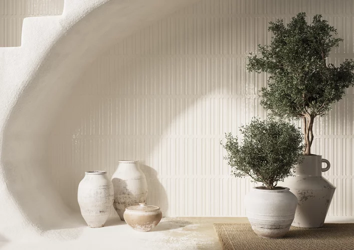 Minimalistyczne wnętrze z błyszczącymi ceramicznymi płytkami ściennymi z kolekcji Monpelli oraz rustykalną ceramiką i roślinami.