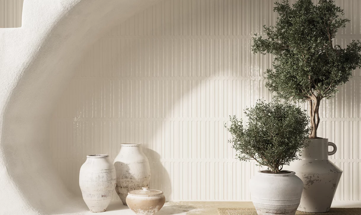 Minimalistyczne wnętrze z błyszczącymi ceramicznymi płytkami ściennymi z kolekcji Monpelli oraz rustykalną ceramiką i roślinami.