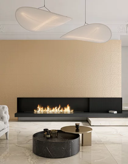 Elegancki salon z polerowanymi płytkami inspirowanymi kamieniem oraz złotymi strukturalnymi płytkami z kolekcji Noisy Whisper i kominkiem.