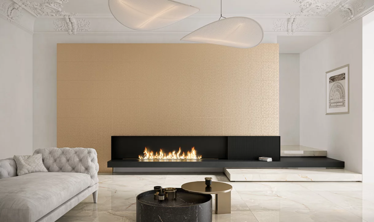 Elegancki salon z polerowanymi płytkami inspirowanymi kamieniem oraz złotymi strukturalnymi płytkami z kolekcji Noisy Whisper i kominkiem.