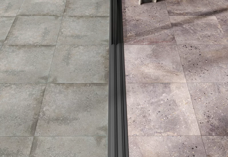 Taras z szarymi płytkami imitującymi beton z kolekcji Path i beżowymi płytkami kamieniopodobnymi.