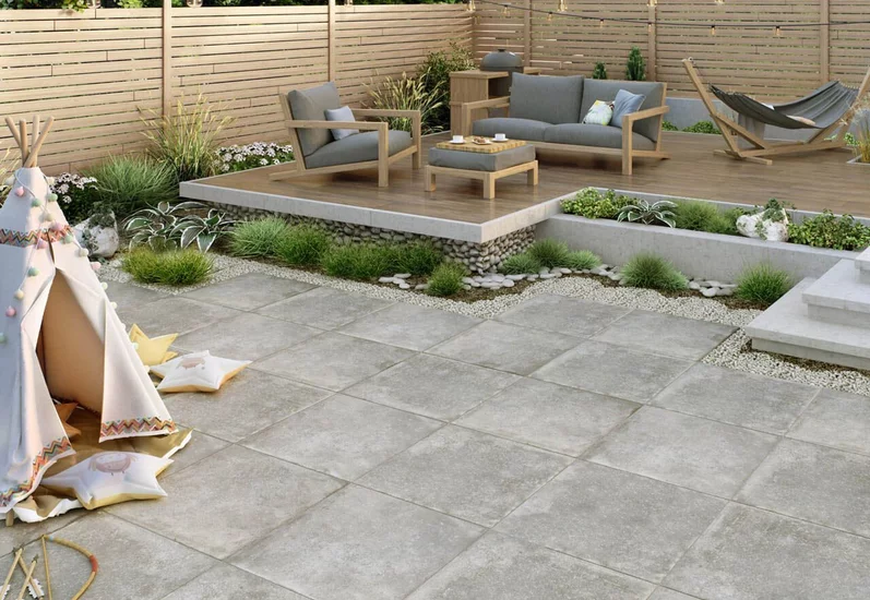 Taras z dużymi płytkami imitującymi beton z kolekcji Path i podestem z płytek drewnopodobnych.