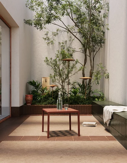 Minimalistyczny dziedziniec z jasnobeżowymi płytkami klinkierowymi z kolekcji Sundown i roślinami.