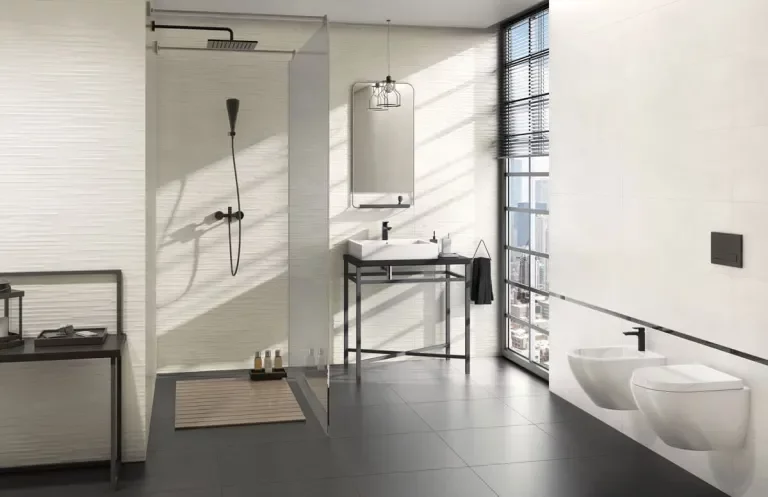 Nowoczesna łazienka z białymi gładkimi i fakturowanymi płytkami na ścianach oraz ciemnymi płytkami imitującymi beton na podłodze.