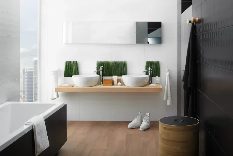 Nowoczesna łazienka z białymi i czarnymi płytkami na ścianach oraz drewnopodobną podłogą i drewnianą umywalką.
