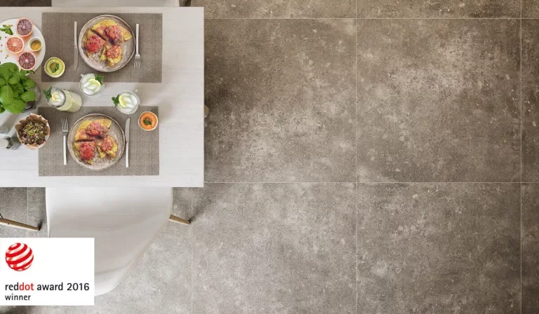 Nowoczesna jadalnia z dużymi płytkami kamieniopodobnymi na podłodze i minimalistycznym białym stołem z krzesłem.