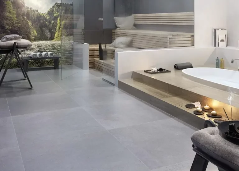 Nowoczesna łazienka inspirowana spa z płytkami imitującymi beton na podłodze i kamieniopodobnymi wokół wanny.