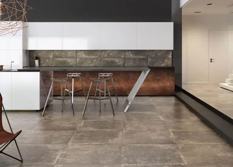 Nowoczesna kuchnia z dużymi płytkami kamieniopodobnymi na podłodze i backsplashu oraz białymi szafkami i metaliczną wyspą.