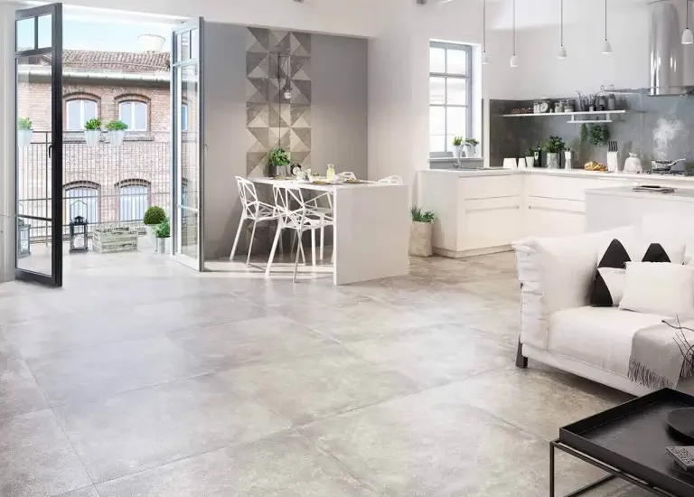 Nowoczesna przestrzeń dzienna z dużymi szarymi płytkami kamieniopodobnymi na podłodze i geometryczną ścianą z płytek.