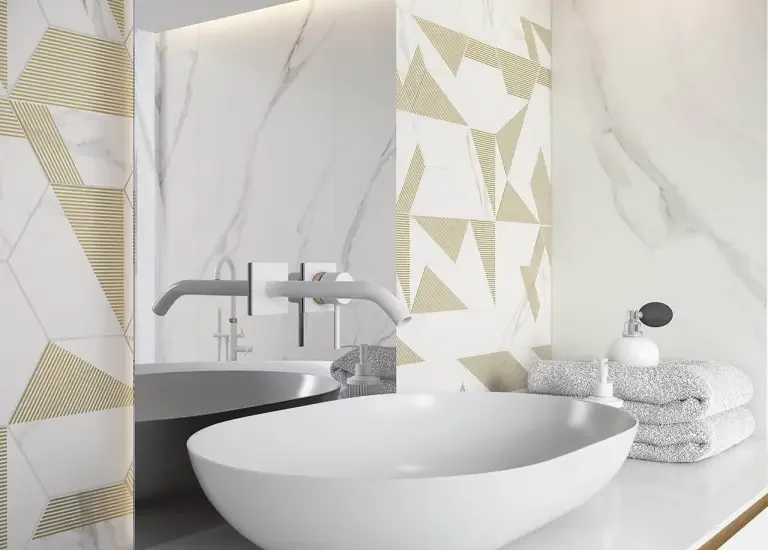 Nowoczesna łazienka z marmurowymi płytkami i geometrycznymi złotymi akcentami oraz białą umywalką.