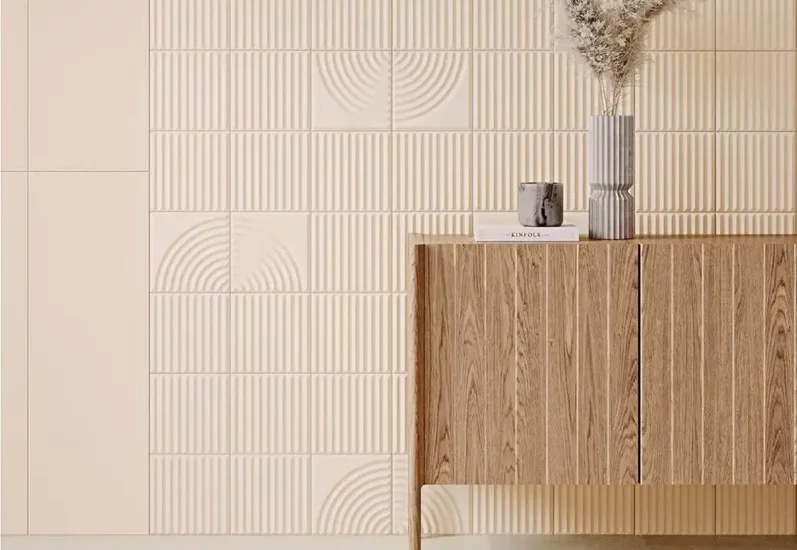 Minimalistyczne wnętrze z gładkimi i fakturowanymi ceramicznymi płytkami na ścianie oraz drewnianą szafką.