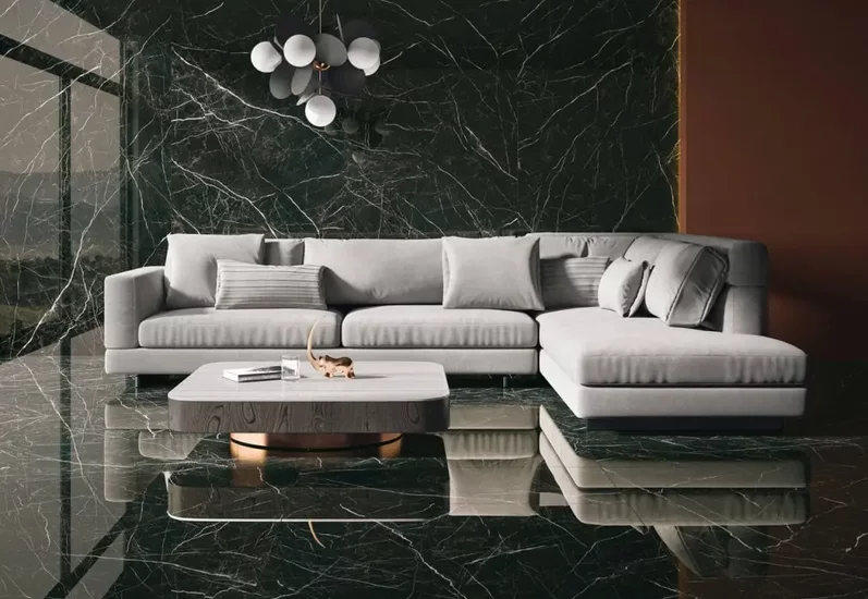 Nowoczesny salon z ciemnozielonymi płytkami marmurowymi na podłodze i ścianie oraz jasnoszarą sofą.