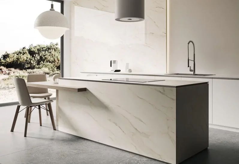 Minimalistyczna kuchnia z wyspą obłożoną płytkami marmurowymi i podłogą z płytek kamieniopodobnych.